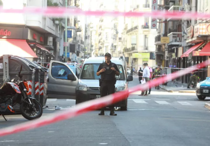 Un agente custodia el vehículo en el que intentaron huir los atracadores de una joyería luego de un tiroteo en la céntrica Avenida Corrientes. FOTO/EFE
