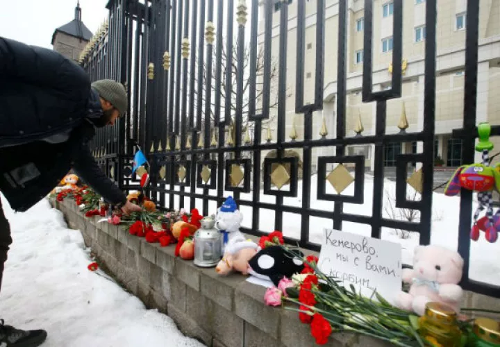 Un hombre observa juguetes mientras recuerda que murieron 41 niños en el siniestro siberiano. Foto: EFE