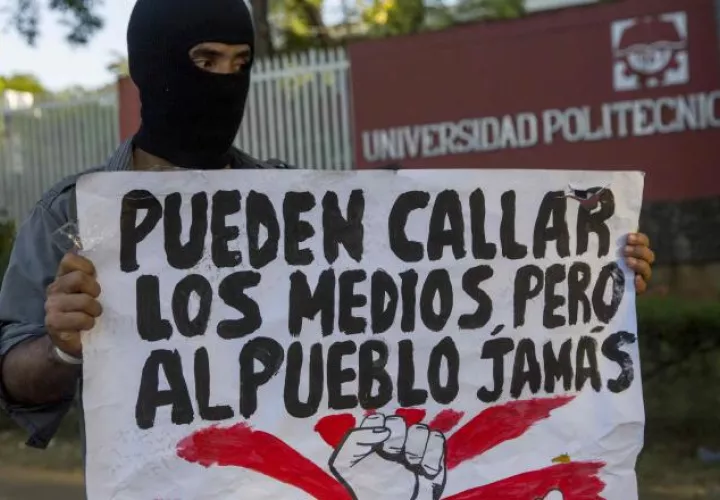 Un joven con una cartel protesta frente a las instalaciones de la universidad politécnica de Nicaragua. EFE