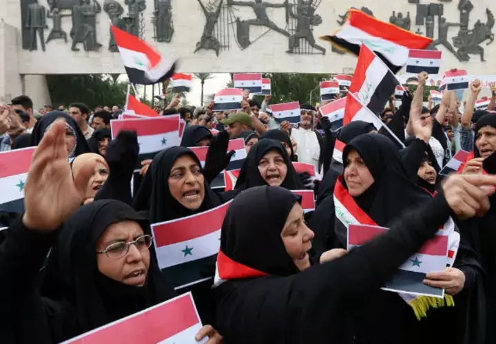 Un grupo de personas ondean banderas de Iraq y Siria, protestando contra el ataque a Siria. FOTO/AP