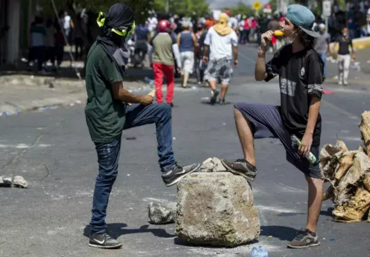 Unos jóvenes hacen un alto en las protestas para refrescarse comiendo helado. FOTO/EFE