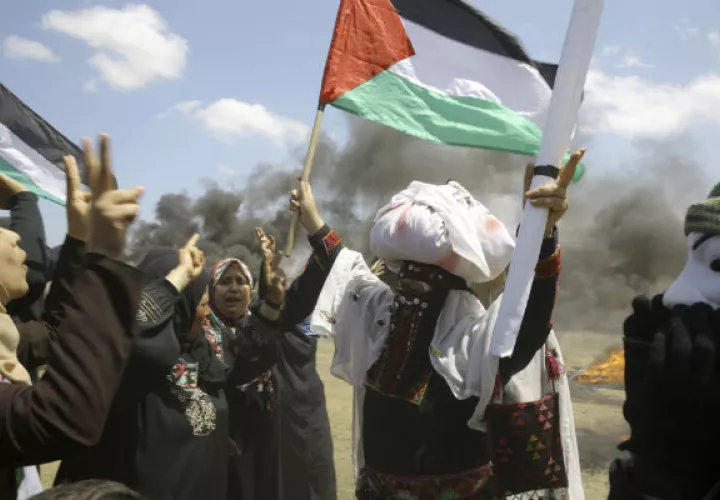 Mujeres palestinas agitan banderas nacionales y entonan consignas. Foto: AP