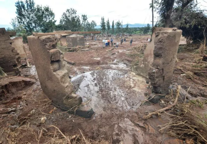Varias personas pasan entre las casas destruidas. Foto: EFE 