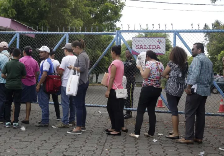 Personas hacen fila para solicitar pasaporte en las oficinas de Migración en Managua. EFE