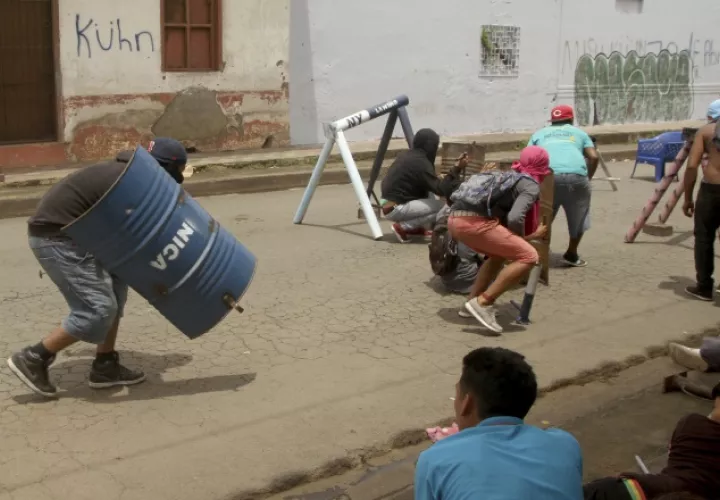 Los manifestantes se defienden con piedras y palos. AP