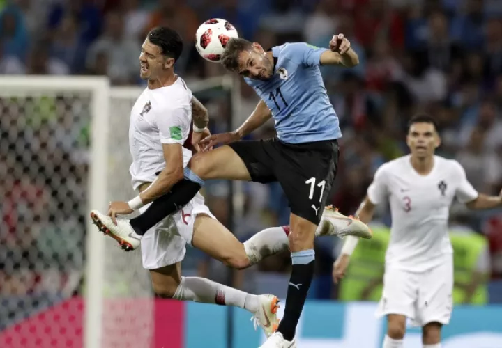 Cristhian Stuani (c) lucha por el balón con el luso José Fonte. /Foto AP