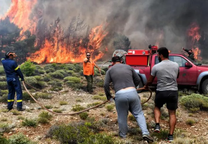 Varios bomberos y voluntarios luchan contra las llamas en un incendio en Verori, cerca de la ciudad de Loutraki (Grecia). EFE