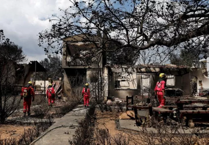 Miembros de la Cruz Roja buscan personas desaparecidastras el incendio en Grecia. EFE