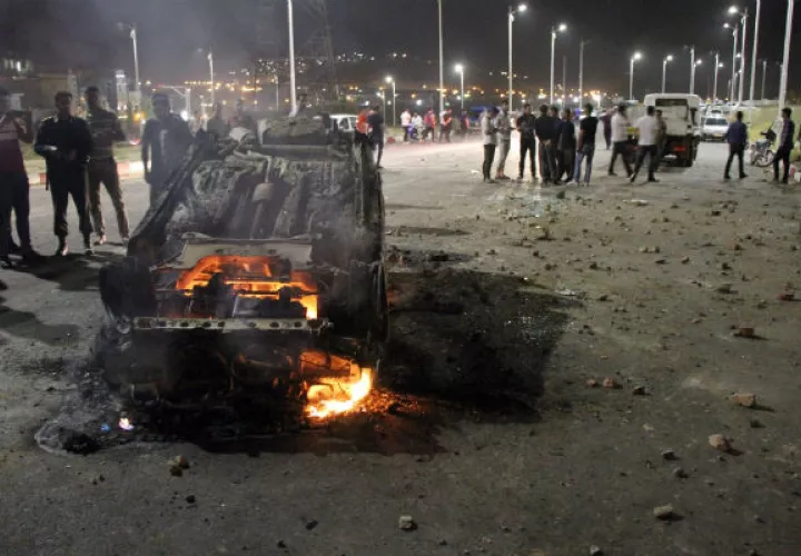 Varios curiosos observan como un coche arde en el lugar del accidente. Foto: EFE 