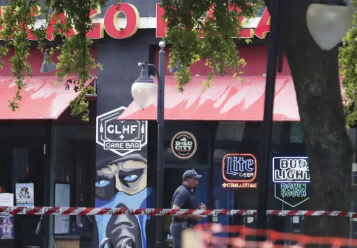 Un policía camina frente al  "Chicago Pizza and GLHF Game Bar" donde ocurrió el mortal tiroteo. Foto: AP. 