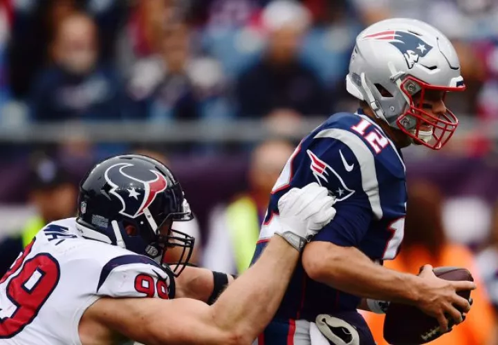 JJ Watt (izq.) intenta frenar el avance de Tom Brady. /Foto EFE