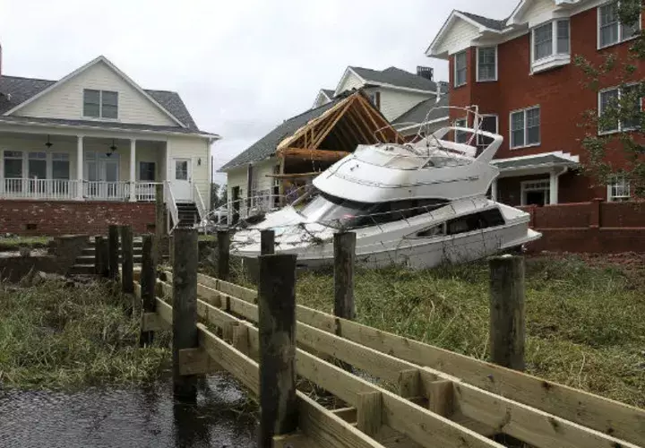 Un bote sin ataduras se sienta detrás de una casa y edificio de condominio en East Front Street después de que fue removido de su muelle por Florence. AP
