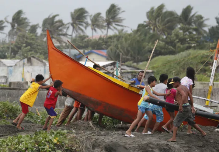 Pescadores y niños aseguran un bote antes de la llegada del tifón Mangkhut. Foto: EFE