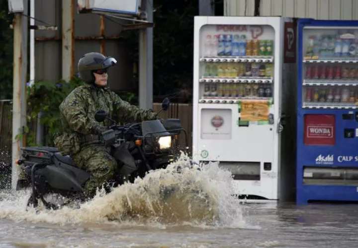 Un miembro de la Fuerza japonesa de Autodefensa pasa en una moto por una calle inundada en Japón. Foto: EFE