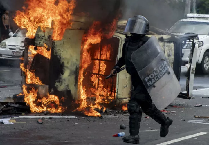 Manifestantes antigubernamentales quemaron el coche policial. Foto: EFE.