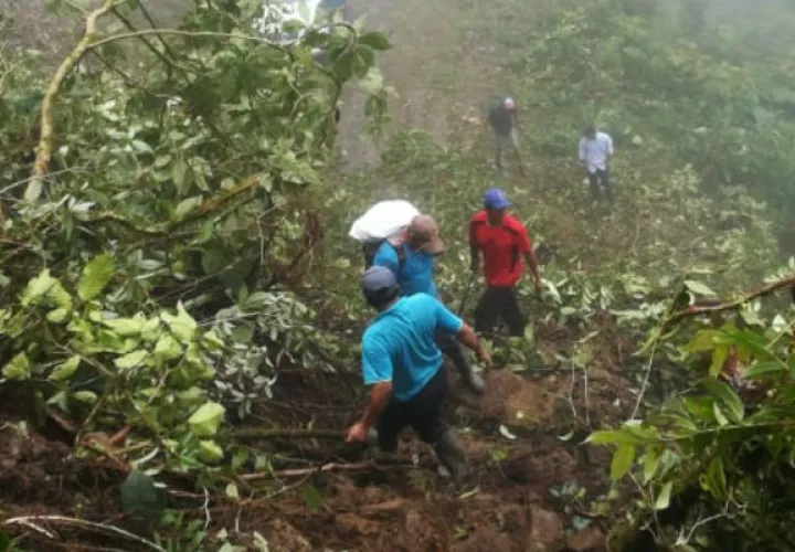 Moradores y docentes arriesgan sus vidas al cruzar en medio del alud de tierra. Foto: Mayra Madrid.
