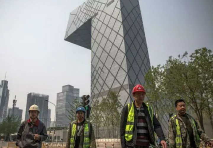 Trabajadores caminan por el distrito financiero de Pekín, en China, cuya economía siguió desacelerándose en el tercer trimestre. EFE