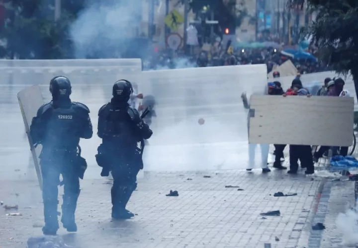 Manifestantes se cubren de los miembros de la Policía antidisturbios en la Plaza de Bolívar. FOTO/EFE