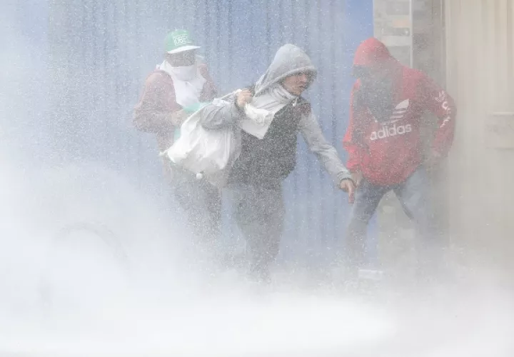  Tres personas llevan bolsas con elementos luego de ingresar a un local comercial saqueado durante las protestas, en un sector de Patio Bonito, sur de Bogotá. FOTO/EFE