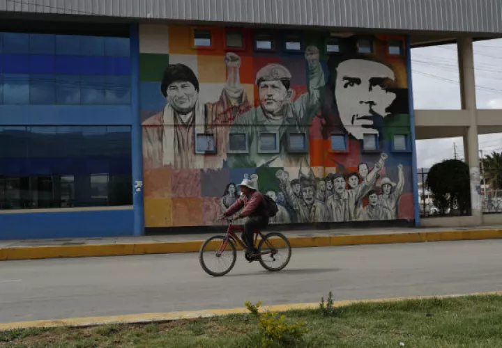 Un ciclista pasa por un mural en una calle boliviana donde aparece el rosto del "Ché" Guevara. Foto: AP. 