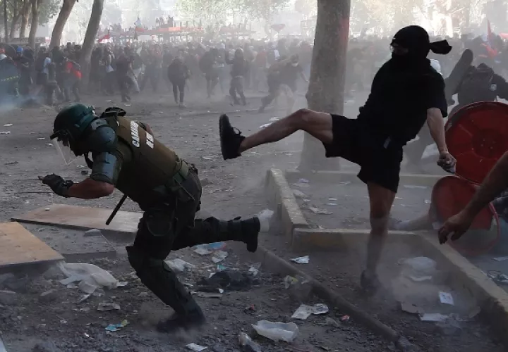 Un carabinero es agredido por uno de los manifestantes en Chile. FOTO/AP