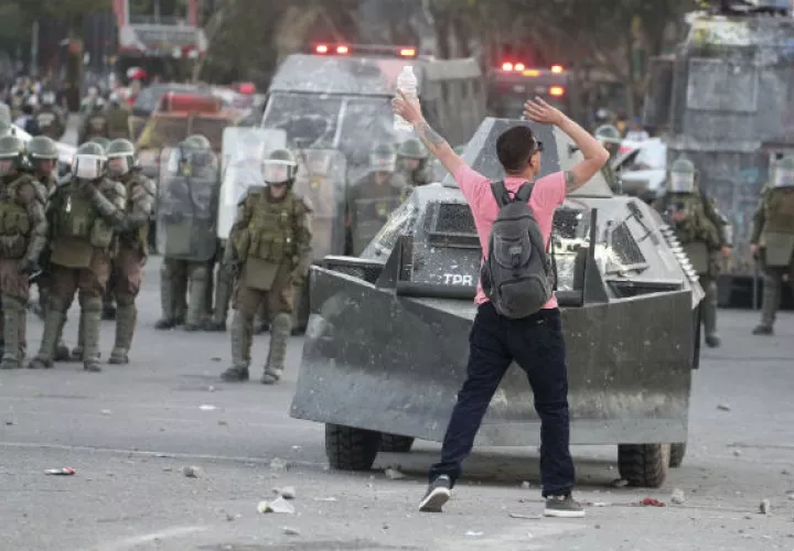 Manifestante chileno frente a policías antidisturbios en Santiago. Foto: AP.