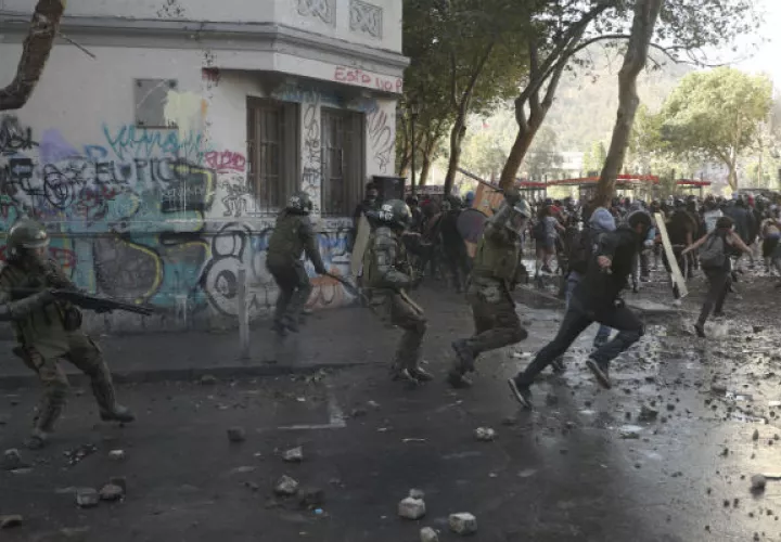 Manifestante chileno frente a policías antidisturbios en Santiago. Foto: AP.