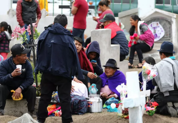 Indígenas comen sobre las tumbas en la celebración del Día de Muertos en Calpi, provincia de Chimborazo, Ecuador. Foto.EFE.