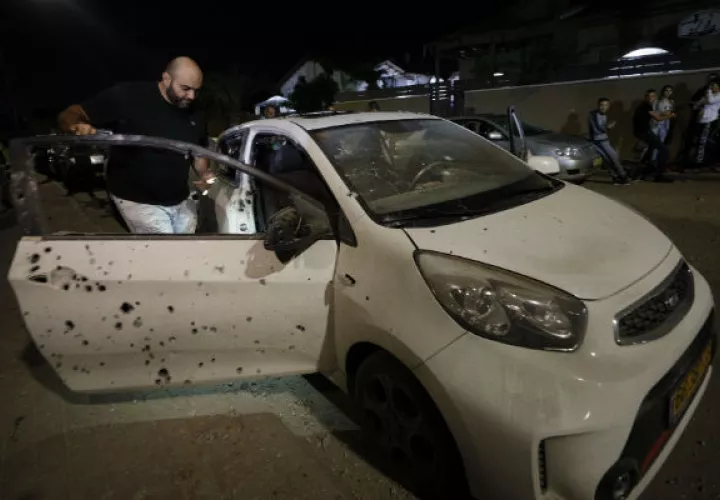 Un  israelí observa su vehículo impactado por misiles tirados desde la Franja de Gaza. Foto: AP. 
