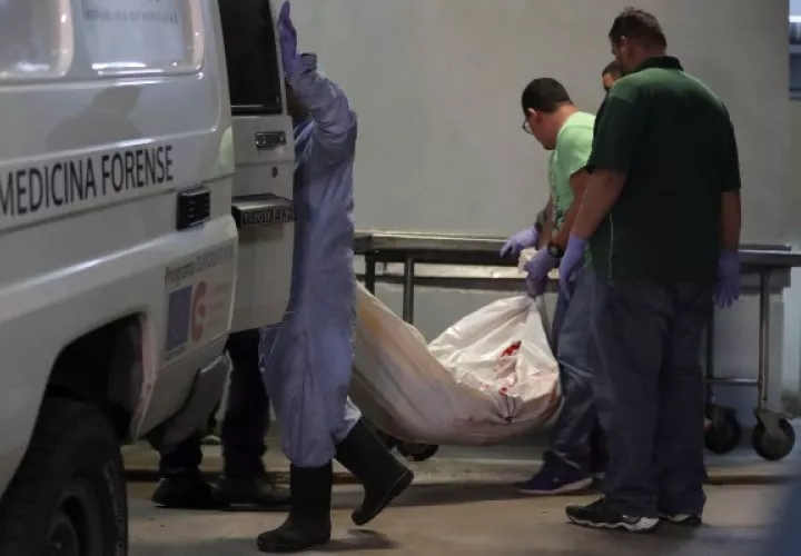 Técnicos de medicina forense de la morgue de Tegucigalpa trasladan el cuerpo de uno de los 18 reclusos muertos en un enfrentamiento entre bandas rivales registrado este domingo en una cárcel cercana a Tegucigalpa (Honduras), en el municipio de El Porvenir, departamento central de Francisco Morazán. FOTO/EFE