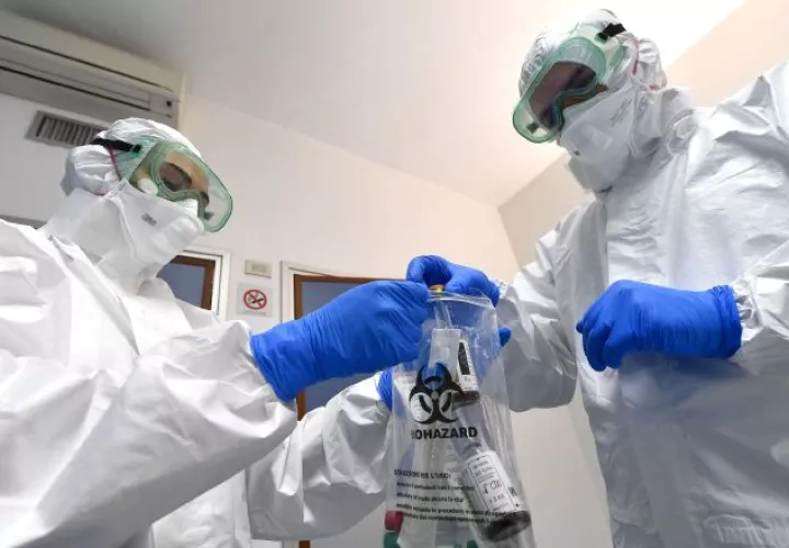 Médicos italianos con protección aíslan artículos contaminados. EFE.
