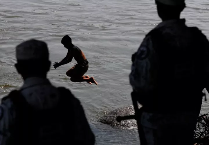 Migrantes hondureños se bañan en el río Suchiate mientras un miembro de la Guardia Nacional de México está de guardia en Ciudad Hidalgo, en la frontera mexicana con Guatemala. FOTO/AP