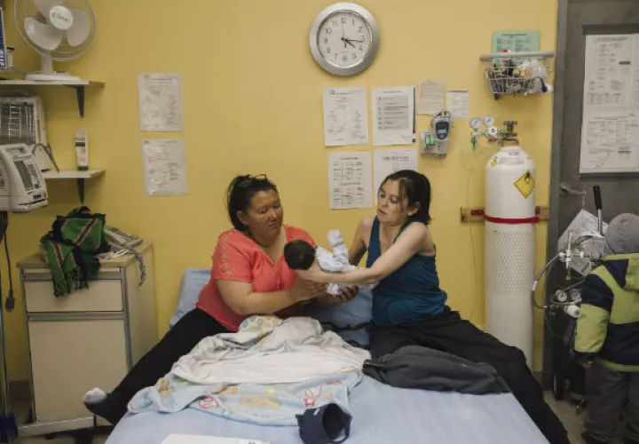 Las mujeres inuit como Susie Mina (primera izq.) ahora pueden dar a luz cerca de casa. Con su hijo y Brenda Epoo, una partera. Foto / Amber Bracken para The New York Times.