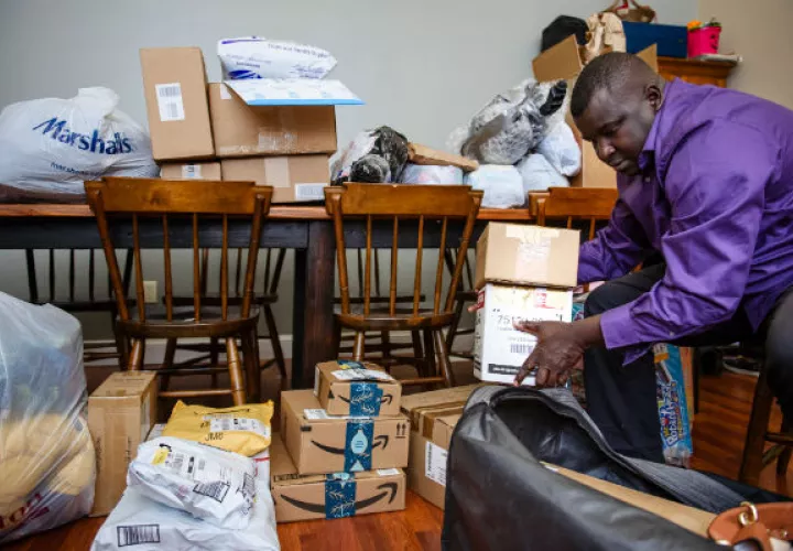 Aly Thioye se volvió mensajero para pagar visitas a Senegal. Prepara paquetes en su hogar en Rhode Island. Foto / Monica Jorge para The New York Times.