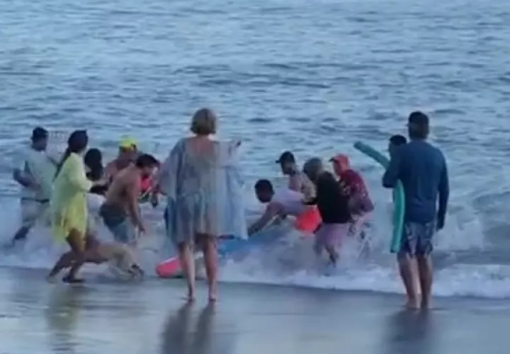 Momento en que un grupo de personas sacaba del mar a la adulta mayor. 