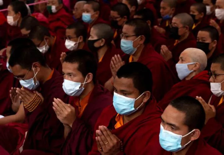 En Katmandú (Nepal), monjes budistas oran con máscaras protectoras.  EFE