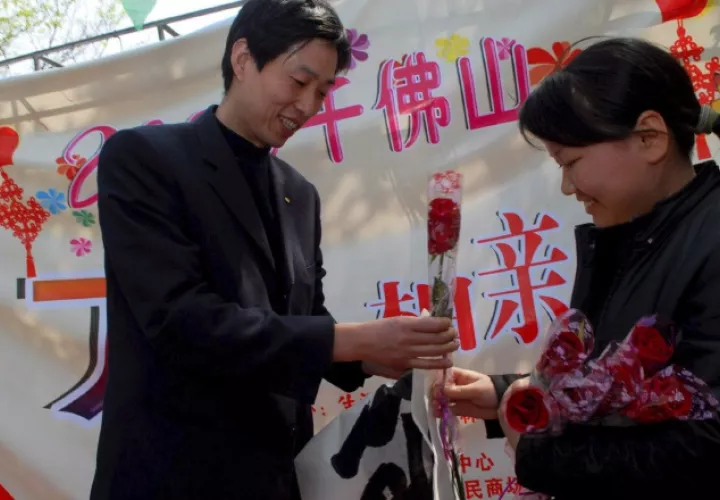 Una mujer que busca pareja entrega una rosa a un hombre en una fiesta en el parque Qianfoshan, en Jinan, provincia de Shandong. EFE/Wu Hong