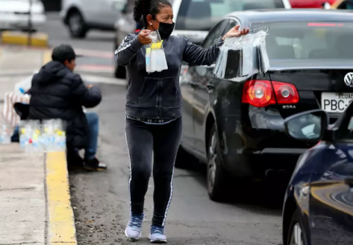 Una mujer con tapabocas vende objetos en las calles de Quito (Ecuador). Foto: EFE.