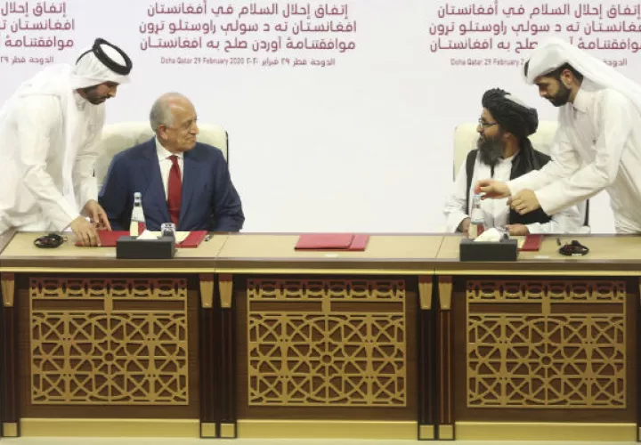 Zalmay Khalilzad, enviado de Estados Unidos, y el Mullah Abdul Ghani Baradar, líder talibán, firman un trato de paz en Qatar. Foto / Hussein Sayed/Associated Press.