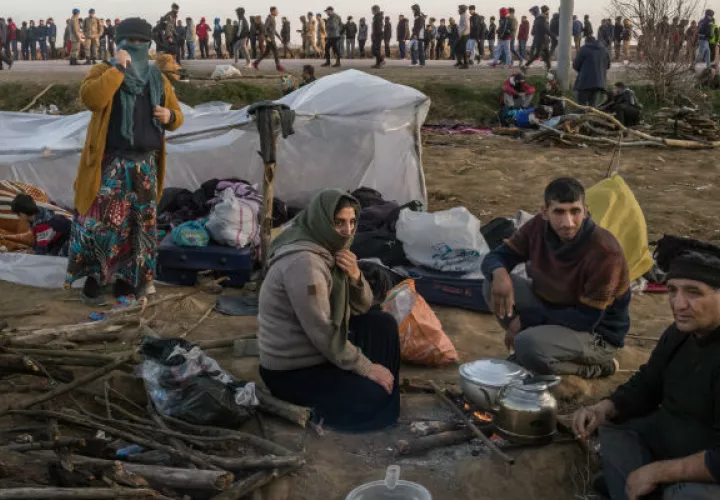 Migrantes descansan mientras cientos más hacen fila para comer en un cruce fronterizo de Turquía con Grecia. Foto / The New York Times.