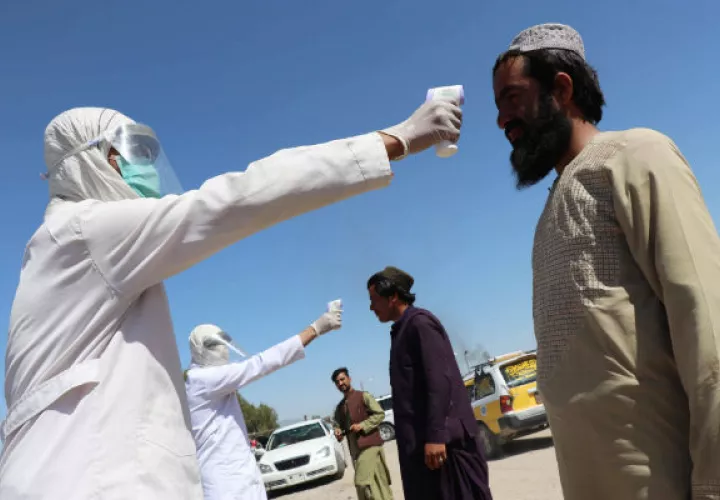 Un trabajador afgano se somete a la toma de temperatura antes de entrar a la ciudad de Kandahar. Fotos: EFE.