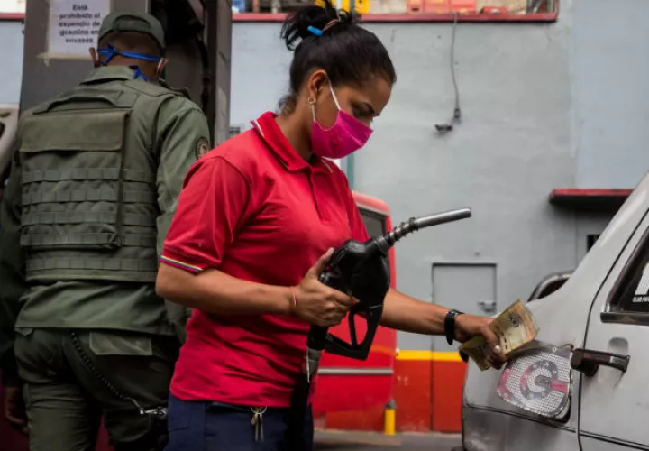 Una mujer en una estación de gasolina carga combustible a un vehículo en Caracas. Fotos: EFE. 