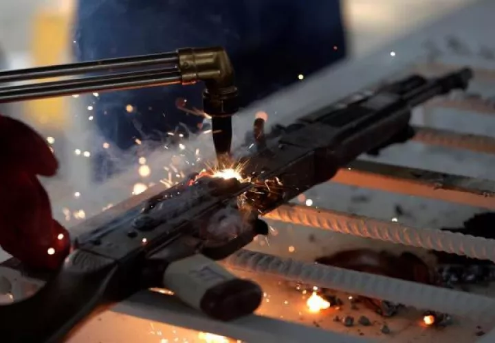 Un hombre corta un fusil con un soplete durante una destrucción de armas 