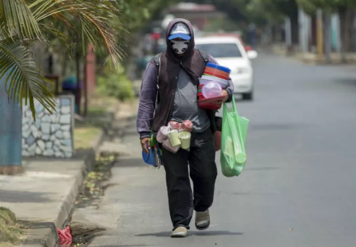 Un vendedor ambulante camina con mascarilla de protección en Managua. Fotos: EFE.