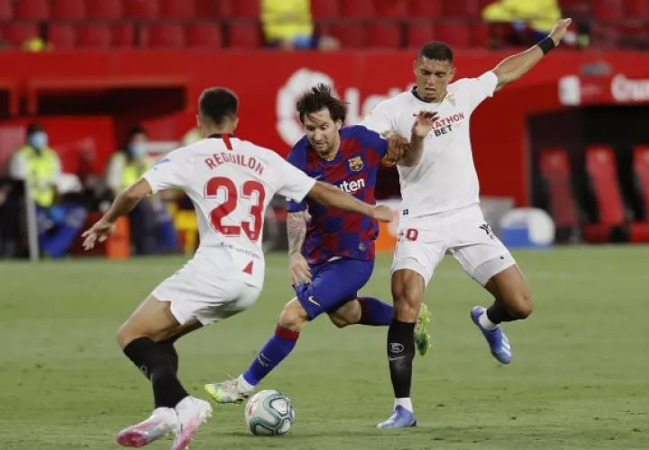 Los defensas del Sevilla, Diego Carlos (der,) y Reguilón (izq.) disputan un balón ante e Leo Messi  del Barcelona. Foto:EFE