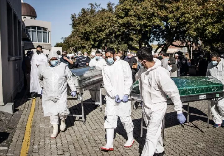 Enterradores cargan ataúdes tras un funeral para víctimas de coronavirus en Ciudad del Cabo en junio. La asistencia a funerales se limita a 50 personas. Foto / Marco Longari/Agence France-Presse — Getty Images.
