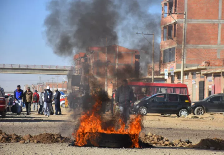 Un hombre cruza un bloqueo de una carretera durante las protestas en Cochabamba. Fotos: EFE.