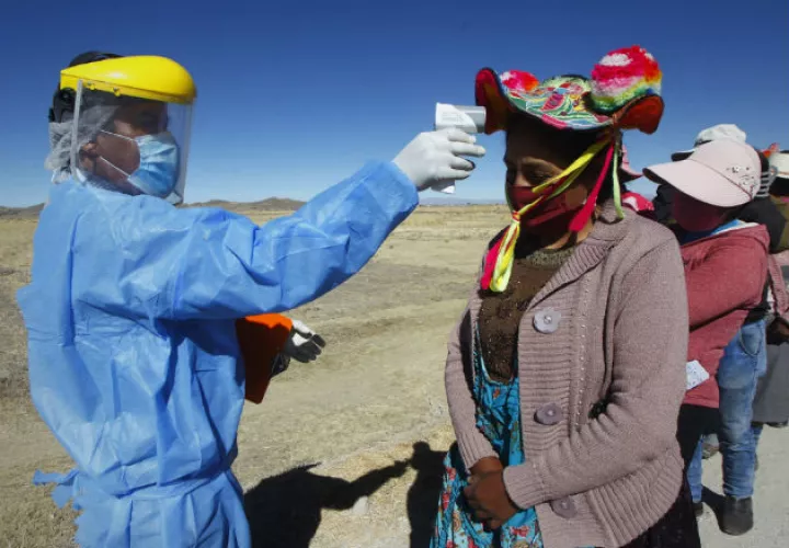 Un hombre toma la temperatura a mujeres Quechuas en la localidad de Coata, a unos cuarenta minutos de la ciudad de Puno (Perú). Fotos:EFE.