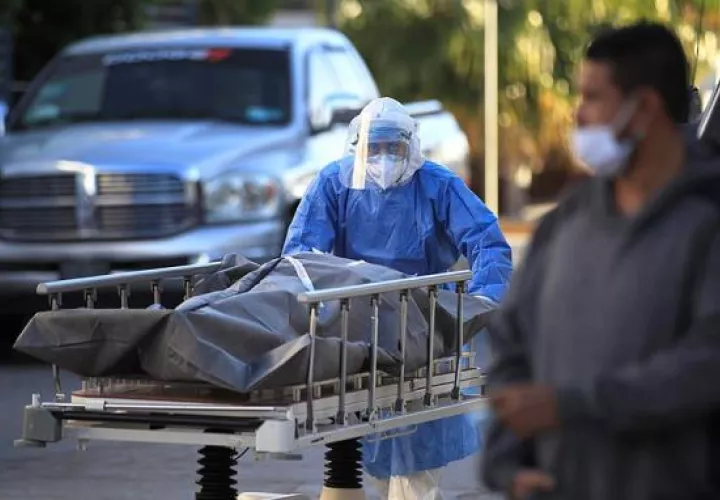 Un paramédico traslada un cuerpo de una persona fallecida por la COVID-19