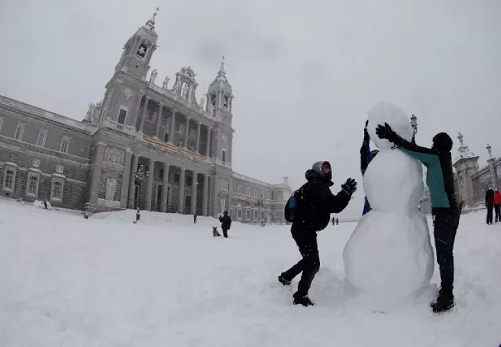 Personas hacen hoy un muñeco de nieve en las inmediaciones de la Catedral de la Almudena , en Madrid. Foto: EFE